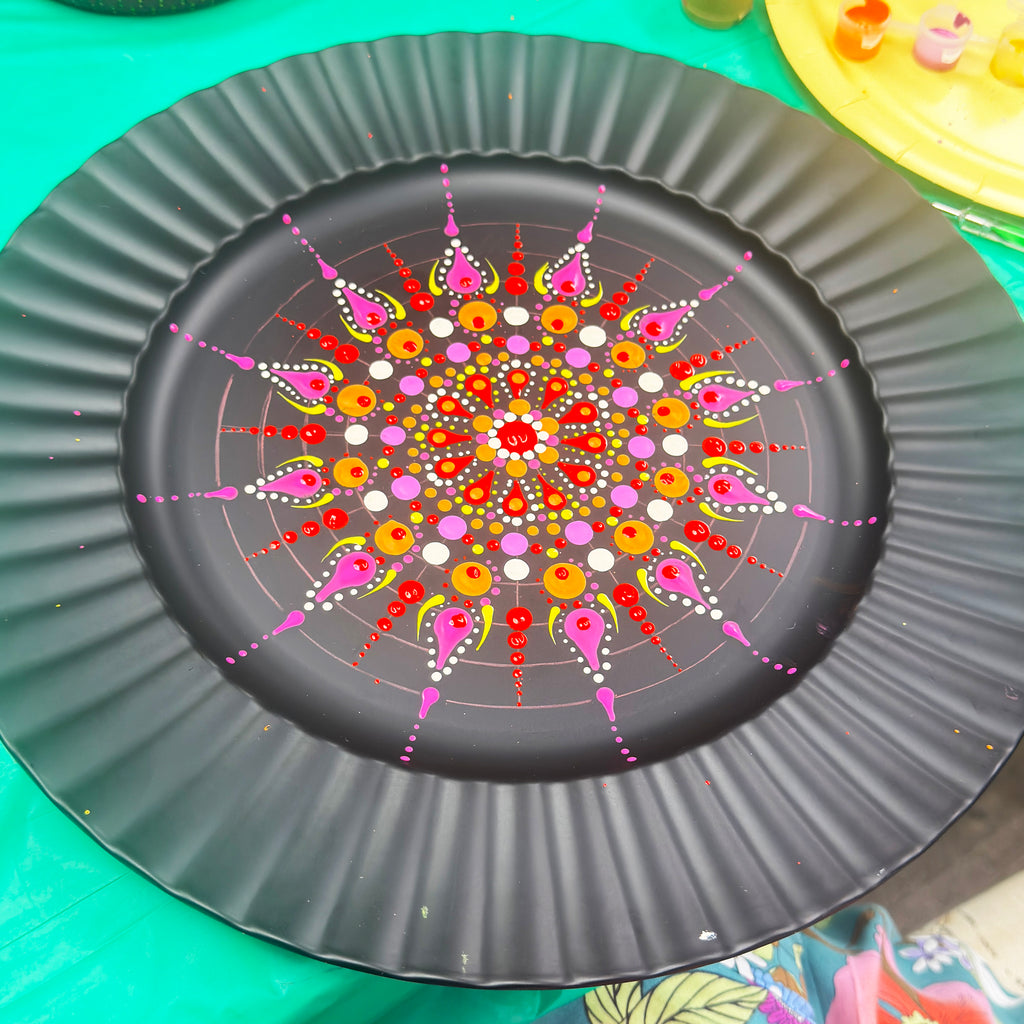 Decorative paper plate with a colorful mandala design on a green surface.