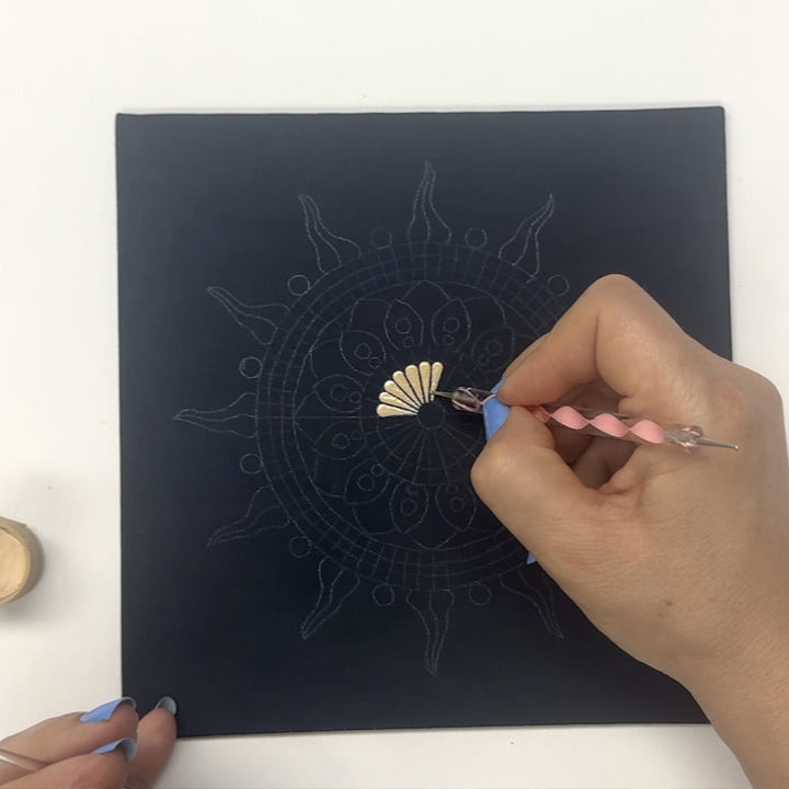 Hand painting a detailed design on a black canvas with a small container of paint and dotting tool